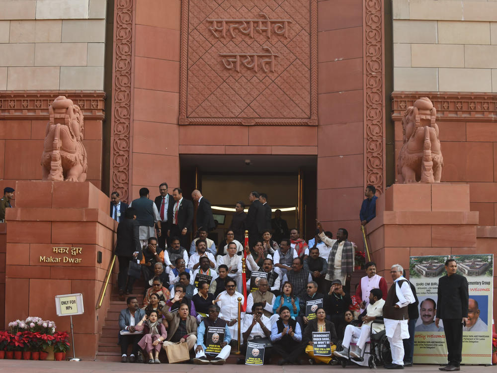 Indian lawmakers sit on the stairs of the Parliament building in protest against the suspension of lawmakers, in New Delhi, Tuesday. Dozens of opposition lawmakers were suspended on Monday after they held a protest demanding the home minister give a statement on the security breach in parliament earlier this month.