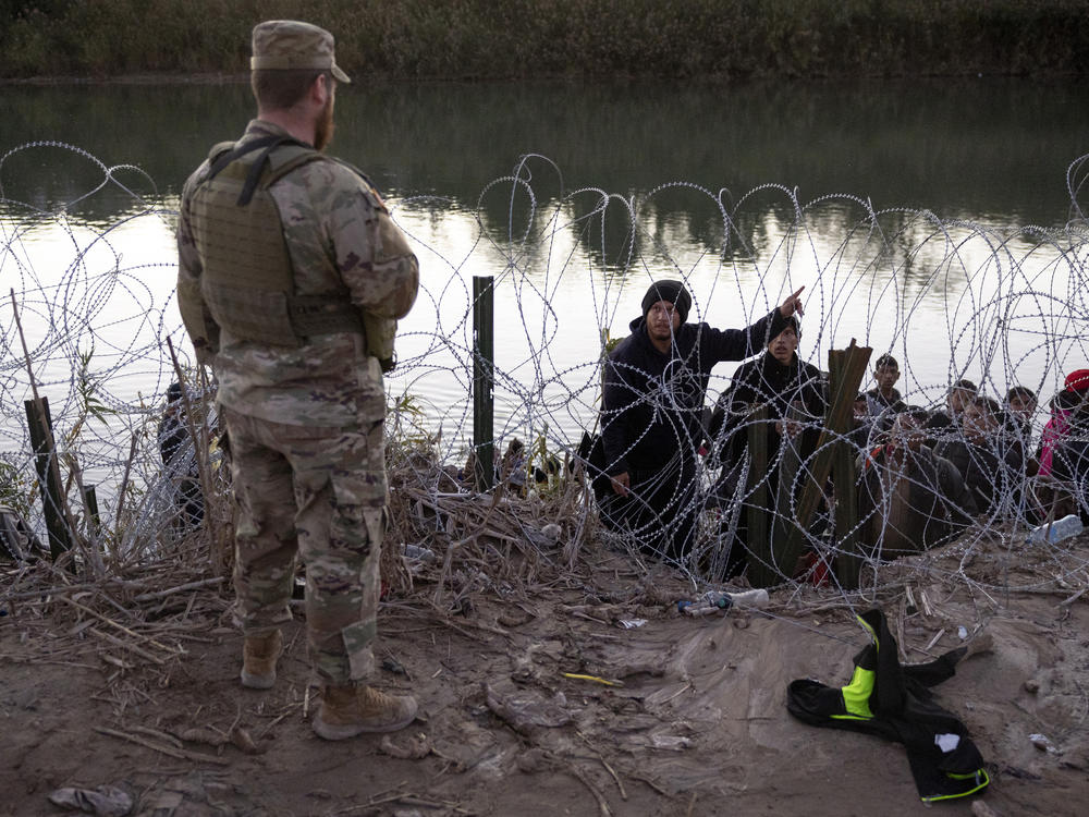 A migrant from Venezuela asks a Texas National guardsman directions to a processing center after crossing from Mexico into the United States on Dec. 17, 2023 in Eagle Pass, Tex.