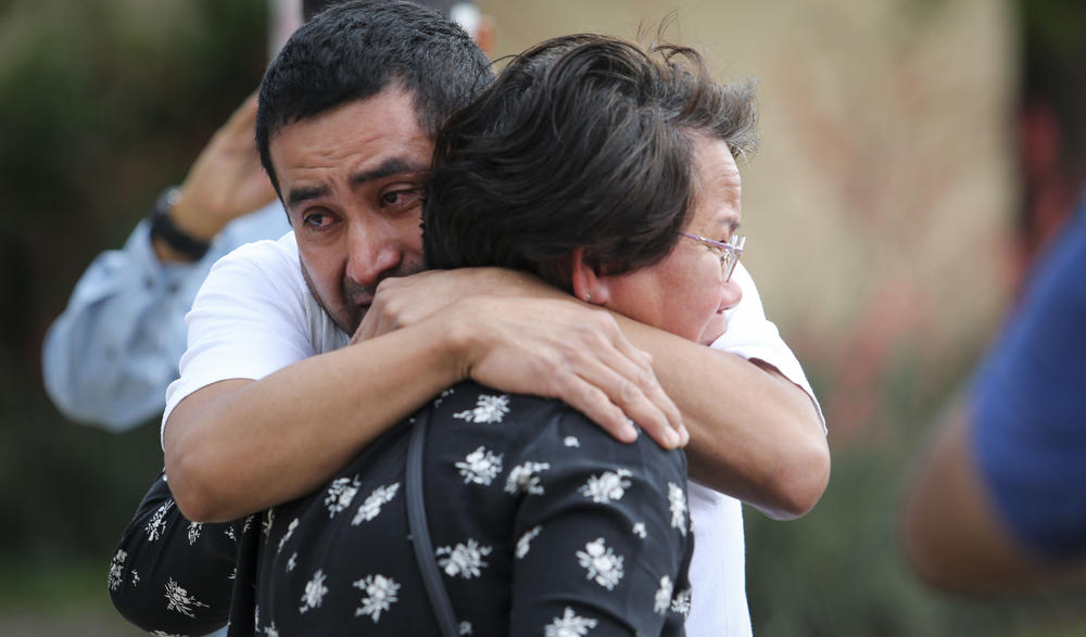 Victor Ramirez and Gina Bennett, both of whom work at the Allen Premium Outlets in Allen, Texas, hug on May 8, 2023, at a memorial for the eight victims of a mass shooting. Full story <a href=