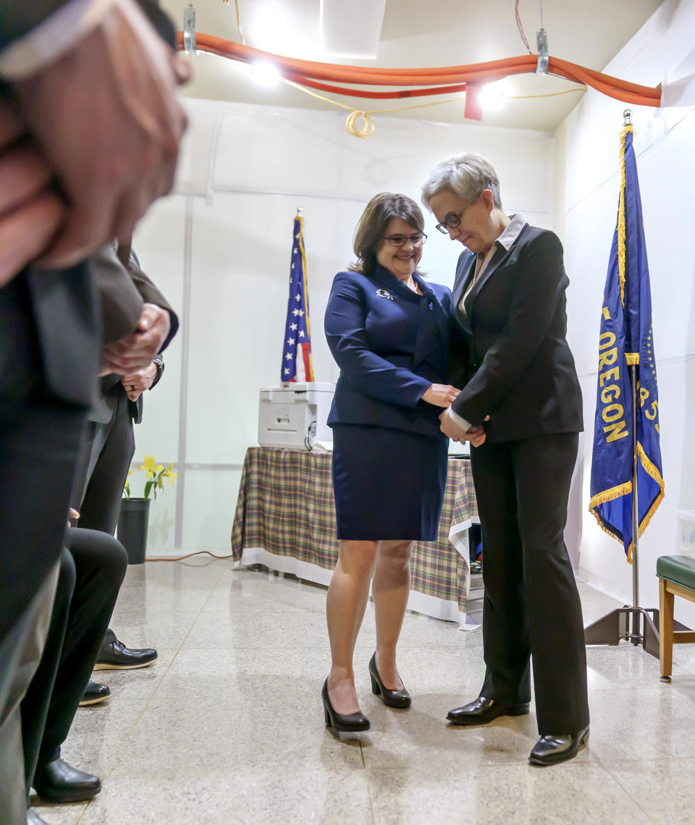 Surrounded by security, Aimee Kotek Wilson (left), and her wife, Gov. Tina Kotek, prepare to enter the inaugural proceedings at the Oregon State Capitol in Salem, Ore., on Jan. 9, 2022. Full story <a href=