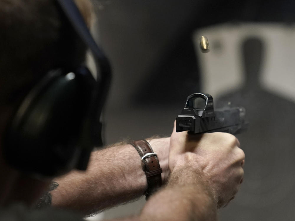 A man fires his pistol at an indoor shooting range during a qualification course to renew his Carry Concealed handgun permit at the Placer Sporting Club, July 1, 2022, in Roseville, Calif.