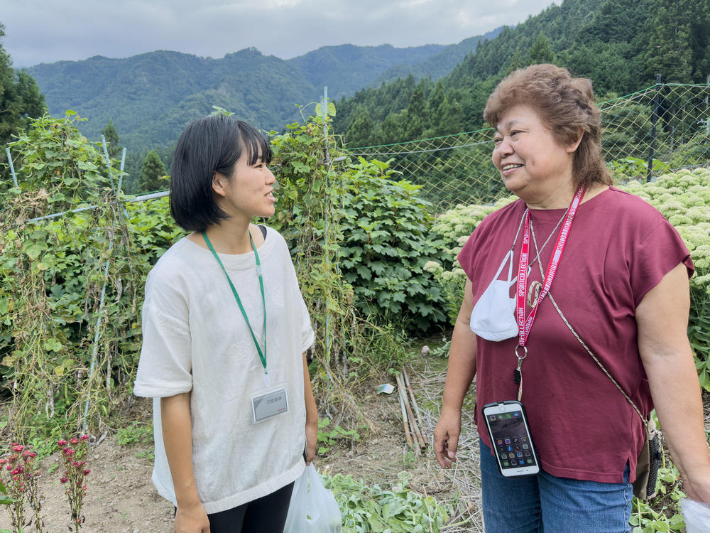 Satomi Oigawa (left) and village resident Tomiko Kanbe talk on a hillside outside the village center. Kanbe helps attract and mentor enterprising young people.