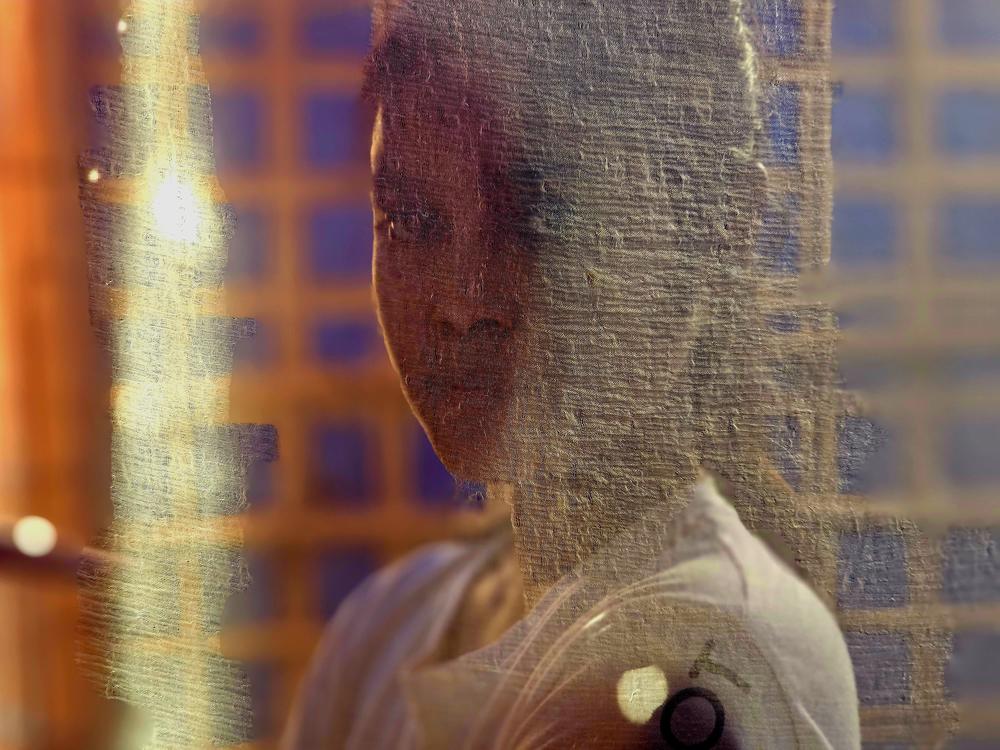 A Rohingya girl poses behind the door of her shelter in the refugee camp in Bangladesh.