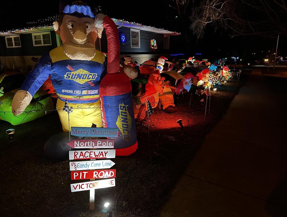 Spotlights shine on dozens of NASCAR inflatables outside a Candy Cane Lane home.