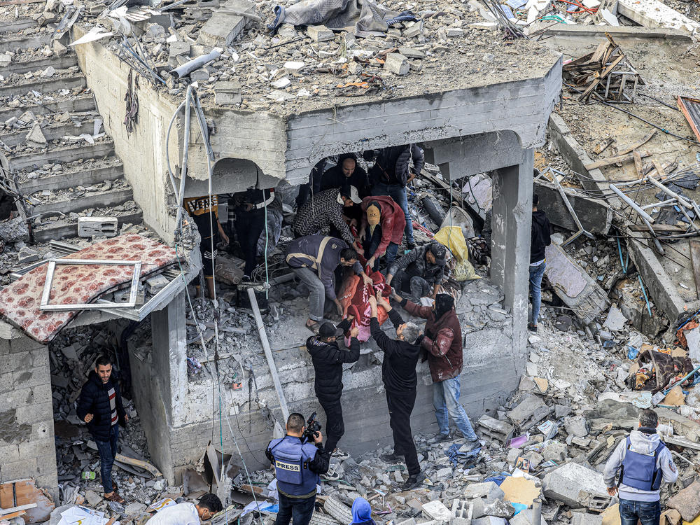 Men recover the body of a Palestinian killed in the aftermath of an overnight Israeli strike at al-Maghazi refugee camp in Gaza on Monday, as the war between Israel and Hamas carries on.