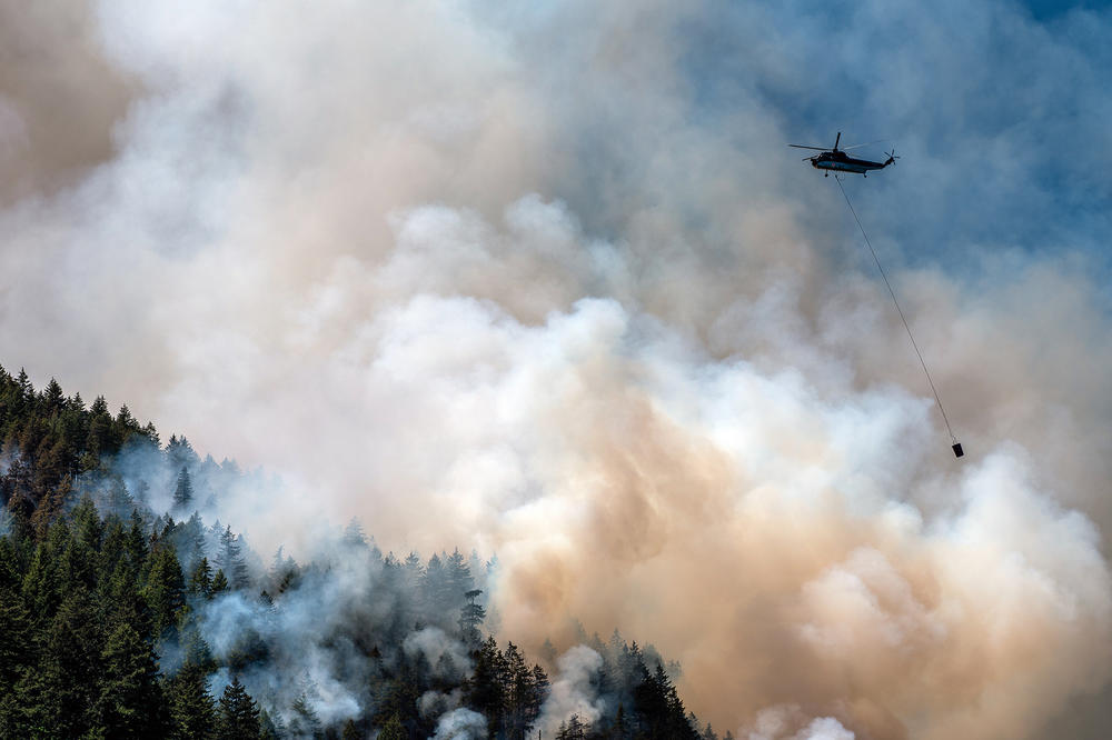 A helicopter flies above a wildfire burning in Canada this summer. Smoke from these wildfires floated hundreds of miles, blanketing much of North America in toxic air.