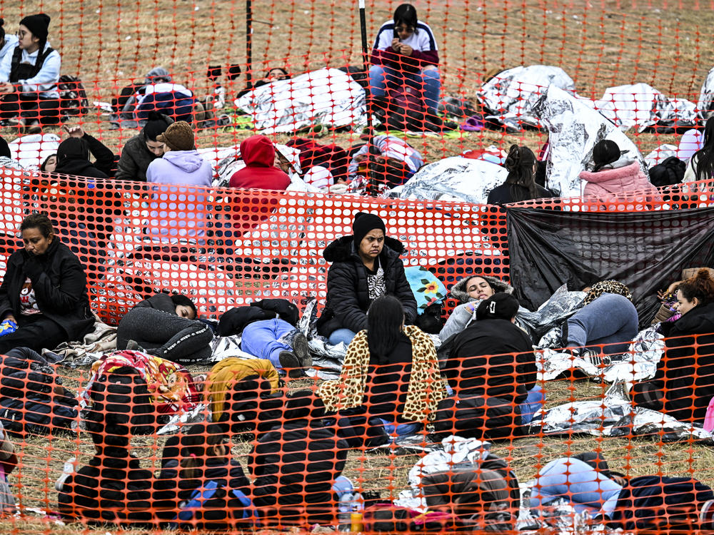 Immigrants wait to be processed after they crossed the border into the U.S. in Eagle Pass, Texas, on Dec. 22. Eleven states and D.C. offer taxpayer-funded health insurance to some immigrants without legal status.