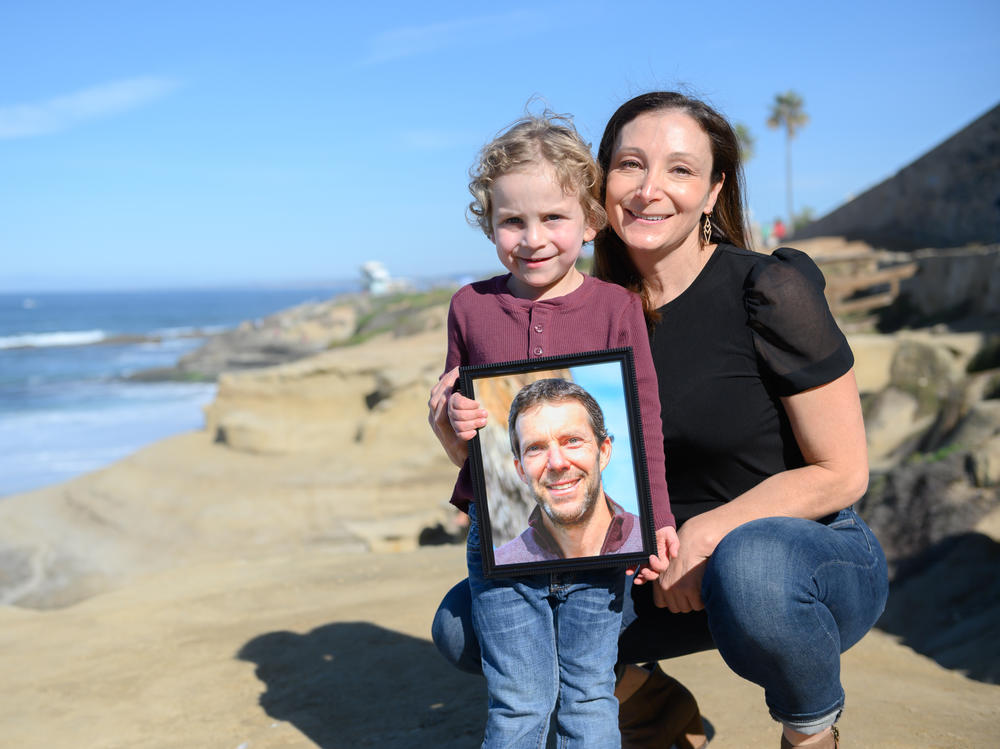 Laura Keenan and her son, Evan, hold a photo of her late husband Matt Keenan, who was killed while riding his bike in San Diego in 2021.