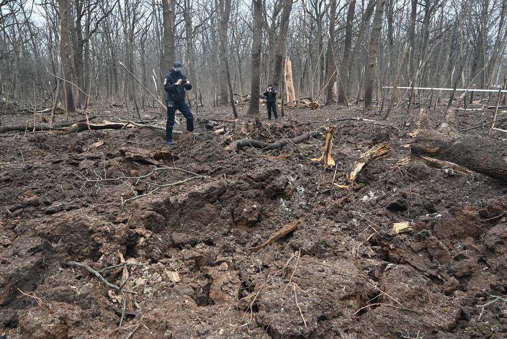 Kharkiv: Ukrainian police officers inspect the site of an explosion after a missile strike in the forest next to a medical complex.