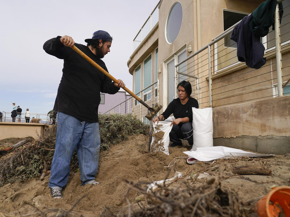 Workers set up sand bags in front of a beachfront property in anticipation of high surf hitting the shore on Friday in Ventura, Calif.