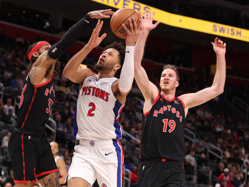 Cade Cunningham #2 of the Detroit Pistons drives to the basket between Gary Trent Jr. #33 and Jakob Poeltl #19 of the Toronto Raptors during the first half at Little Caesars Arena on Saturday in Detroit.