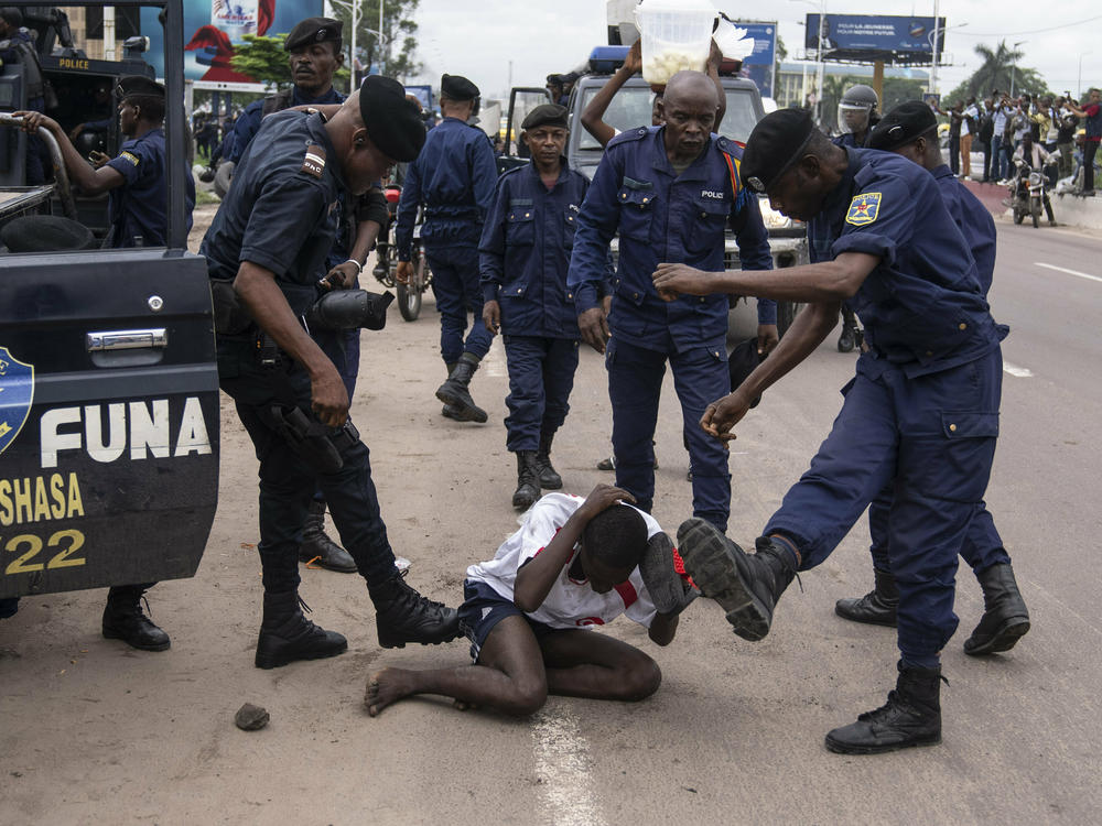 Security forces assault a supporter of presidential candidate Martin Fayulu during clashes outside his party's headquarters, in Kinshasa, Democratic Republic of the Congo, Wednesday, Dec. 27, 2023.