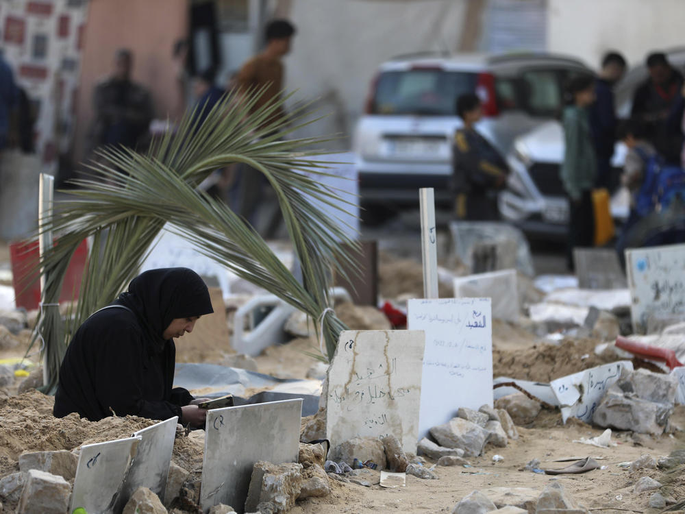 Palestinians visit the graves of people killed in an Israeli bombardment of the Gaza Strip and buried inside the Shifa Hospital grounds in Gaza City, on Sunday, Dec. 31, 2023.