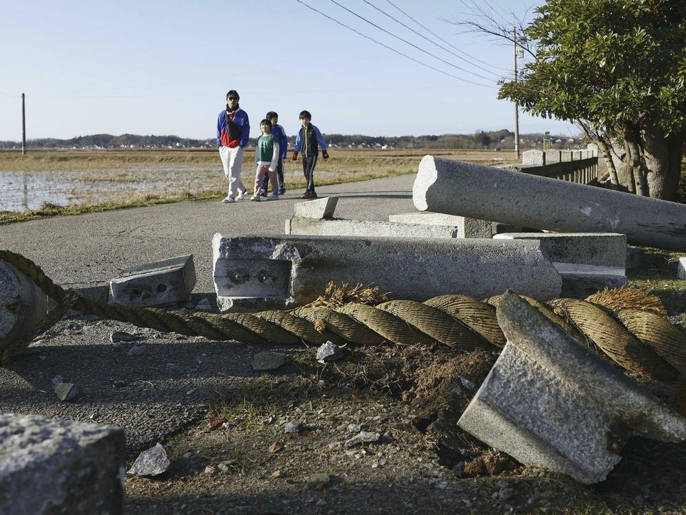 People walk by a torii gate damaged by an earthquake at a shrine in Hakui, Ishikawa prefecture, Japan Tuesday, Jan. 2, 2024.