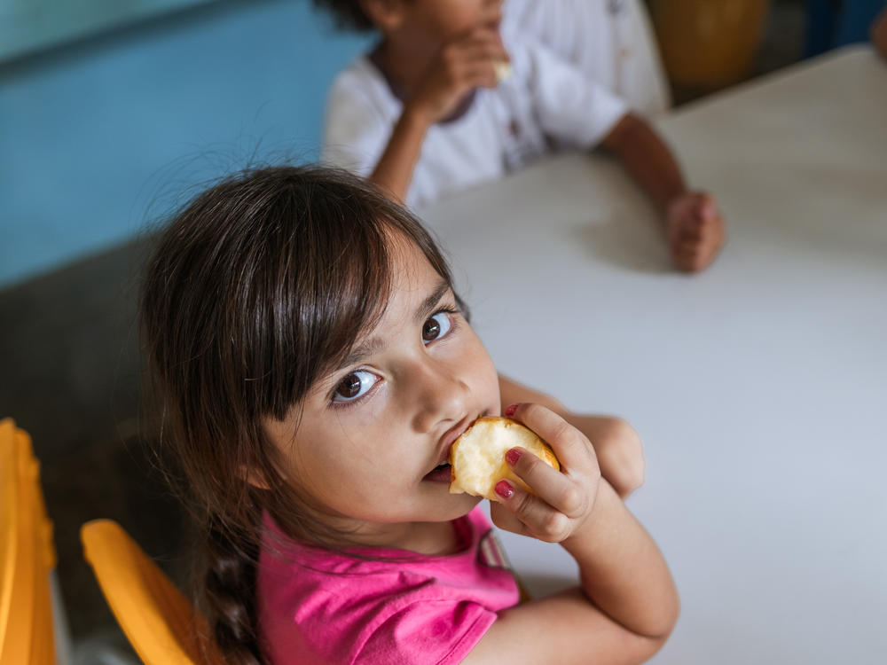 A student at Professor Lourdes Heredia Mello Municipal School in São Paulo enjoys an apple for dessert after lunch. Brazil's school lunch program, enshrined in its constitution, is a pillar of the country's anti-poverty efforts.