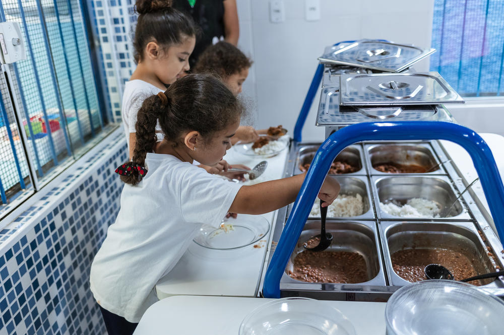 At a buffet-style table students serve themselves lunch. This day's menu includes rice, beans, roast meat with vegetables and cabbage and carrot salad.