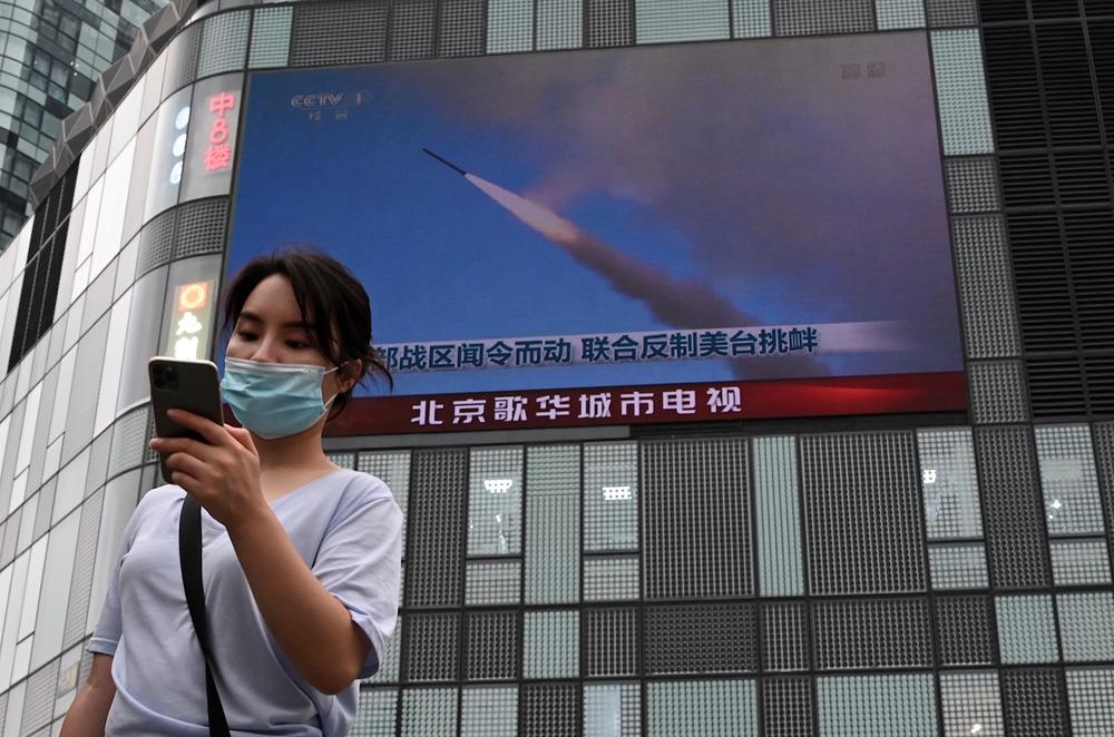 A large screen shows a news broadcast about China's military exercises encircling Taiwan, in Beijing in 2022.