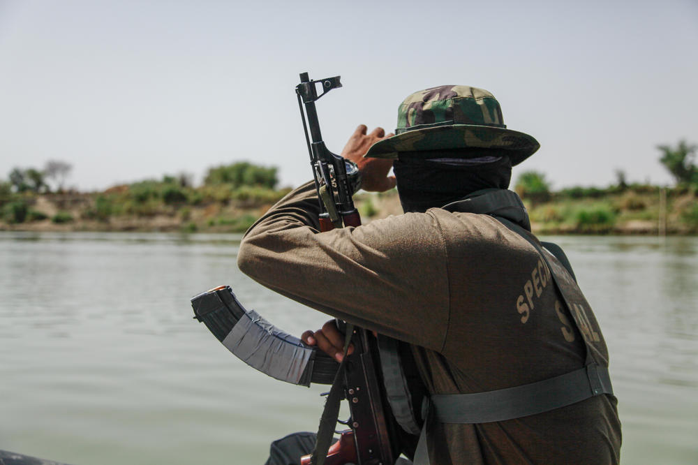 In this photograph taken in April 2022, a Pakistani naval officer guards a documentary team as they boat down a stretch of the Indus River near the southern Pakistani town of Sehwan. Researchers say one challenge they face in observing, or counting, the Indus River dolphin is the lack of security around the river. Outlaws live by the river banks and have attacked researchers in the past.