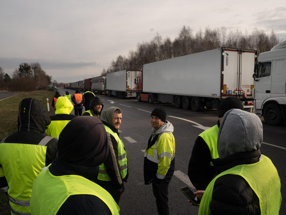 Ukrainian truck drivers stand near a long line of trucks as they wait for days at the Dorohusk border in Poland.