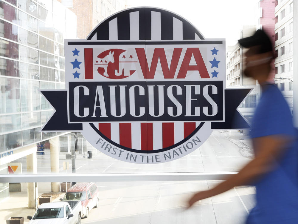 A pedestrian walks past a sign for the Iowa caucuses on a downtown skywalk in Des Moines, Iowa, on Feb. 4, 2020.