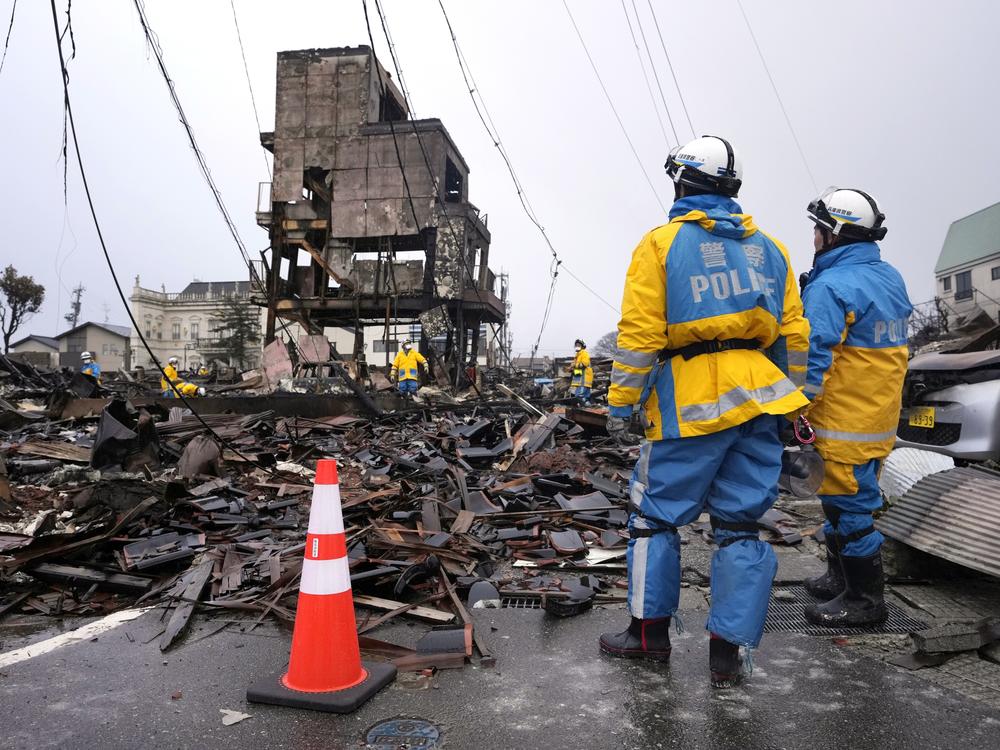 Police officers search for  victims in debris of damaged and burnt buildings in Wajima northwest of Tokyo, on Sunday, Jan. 7, 2024. Monday's temblor decimated houses, twisted and scarred roads and scattered boats like toys in the waters, and prompted tsunami warnings.