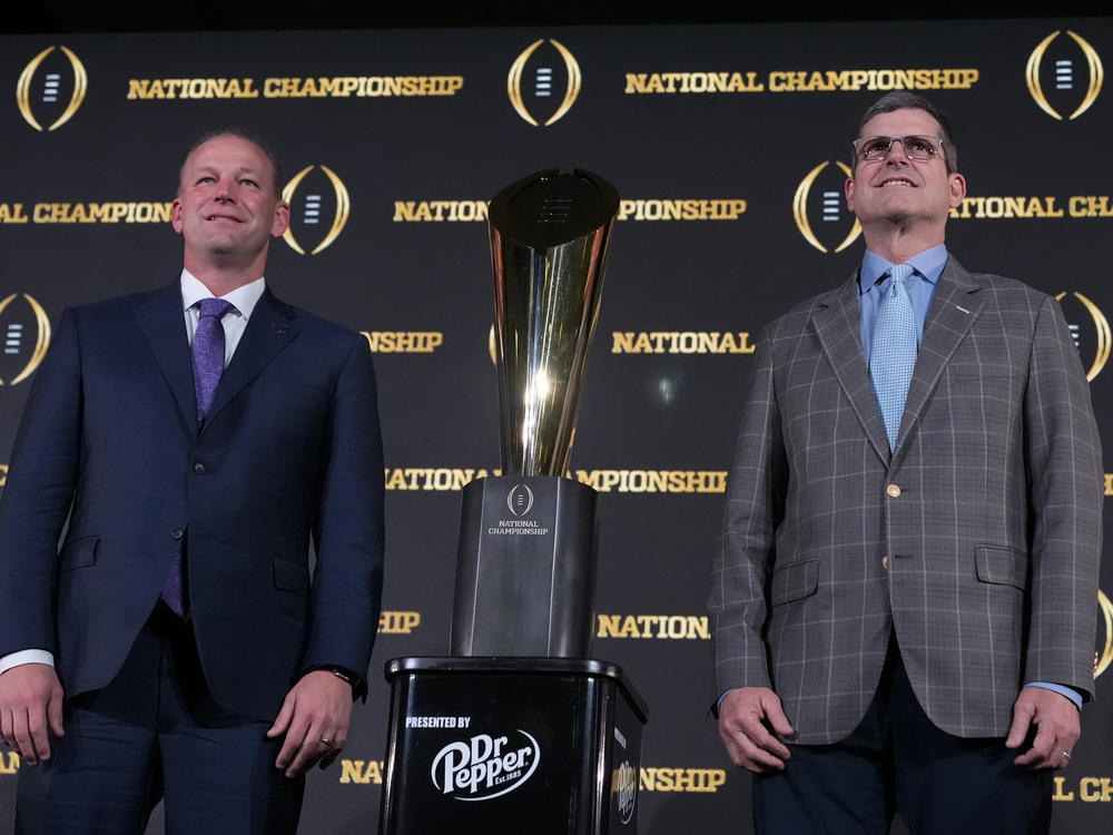 Washington head coach Kalen DeBoer, left, and Michigan head coach Jim Harbaugh pose with the trophy after a news conference ahead of the national championship NCAA College Football Playoff game between Washington and Michigan on Sunday, Jan. 7, 2024, in Houston. The game will be played Monday.