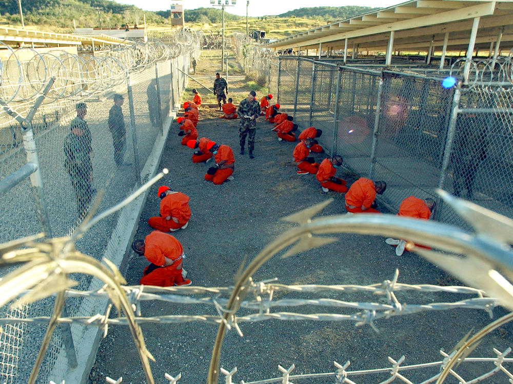 In this handout photo provided by the U.S. Navy, U.S. Military Police guard detainees in orange jumpsuits on Jan. 11, 2002 at Guantánamo Bay, Cuba.