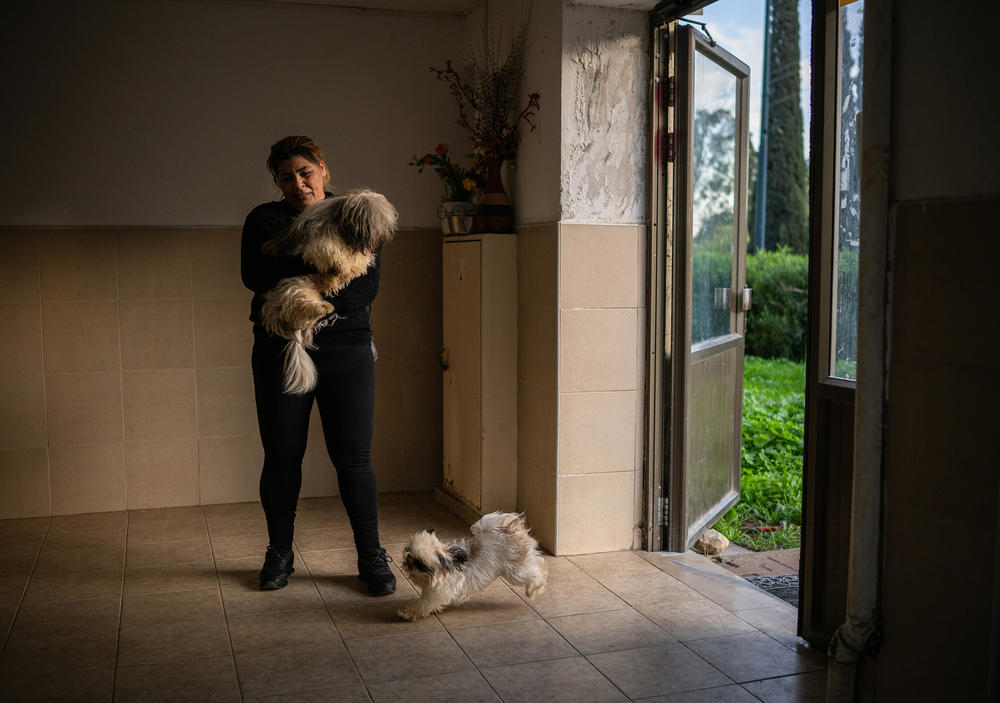 Sisilya al-Ousi takes her dogs out of her apartment building in Kiryat Shmona. Some residents, like Ousi, have chosen to remain.