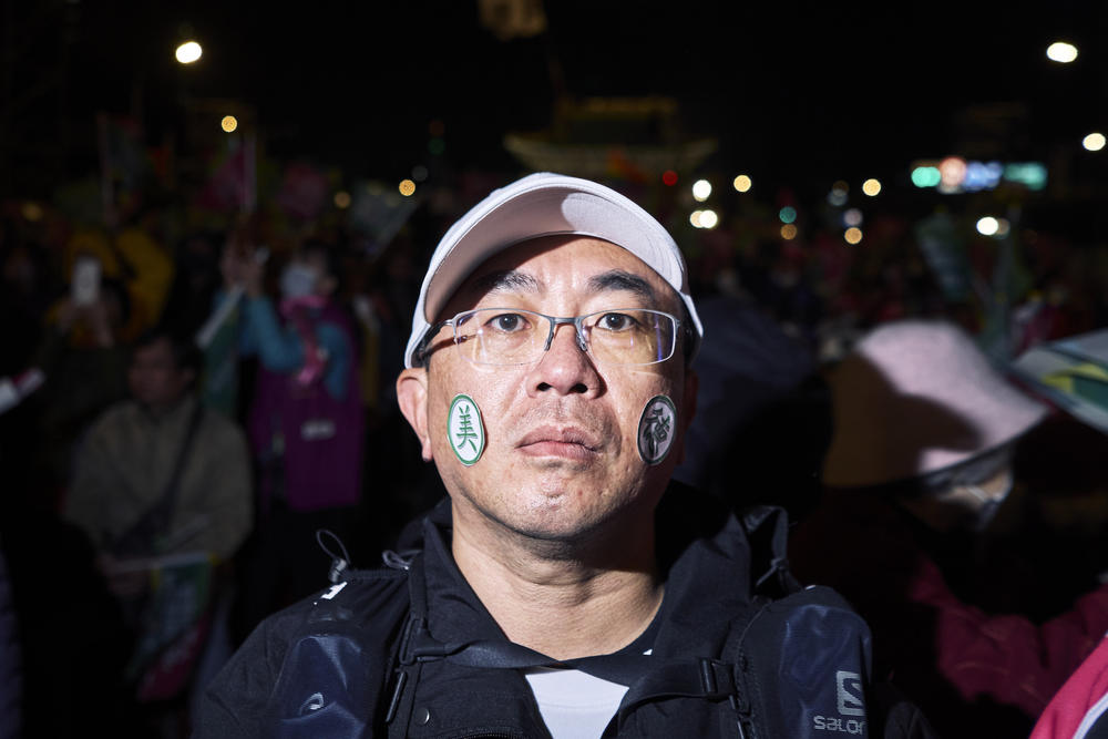 A supporter of DPP wears stickers with the characters for Vice Presidential candidate, Bi Khim Hsiao, left, and Presidential candidate, Lai Ching-Te, right, at one rally.