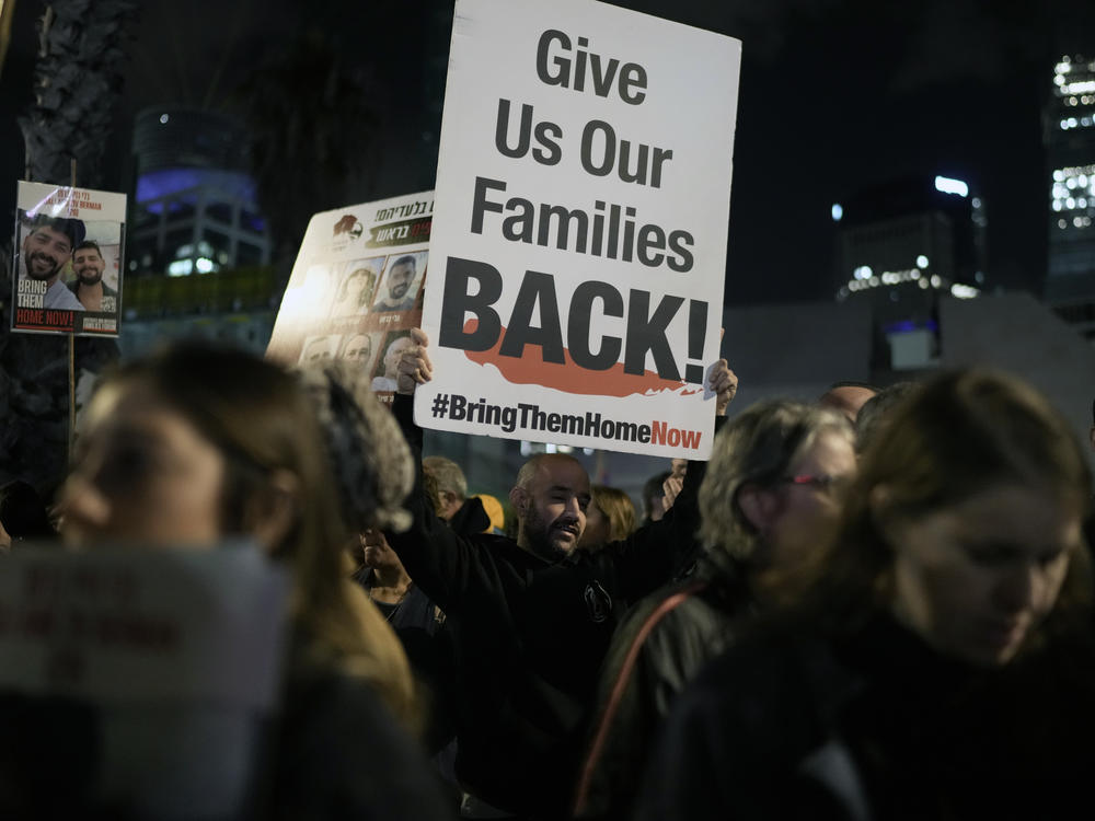 A man holds a sign calling for the release of the hostages taken by Hamas militants into the Gaza Strip during a demonstration at the Hostages Square in Tel Aviv, Israel, Saturday Jan. 13, 2024.