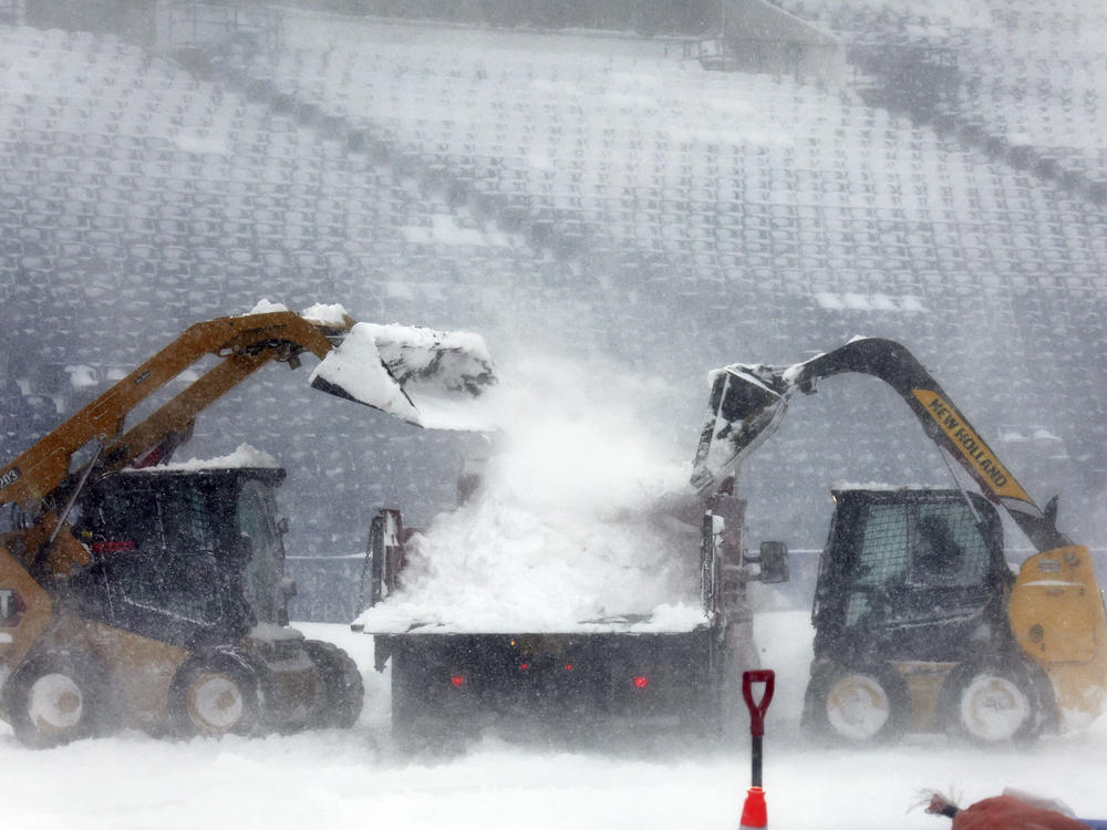Workers remove snow from Highmark Stadium in Orchard Park, N.Y., on Sunday, ahead of Monday's rescheduled NFL playoff game.