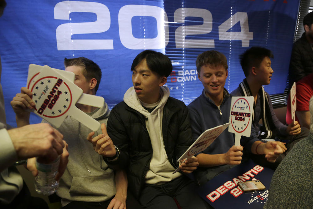 Attendees pass around signs at Ron DeSantis' campaign event in West Des Moines, Iowa on Saturday, Jan. 13, 2024.