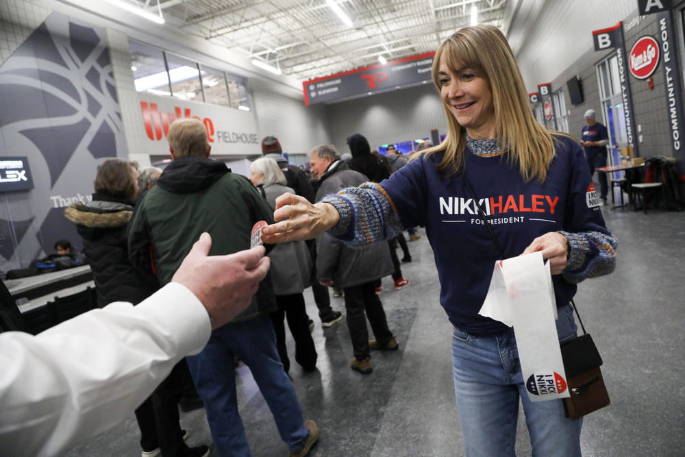 A woman passing out stickers in support of Nikki Haley at the West Des Moines caucus site on Jan. 15, 2024.