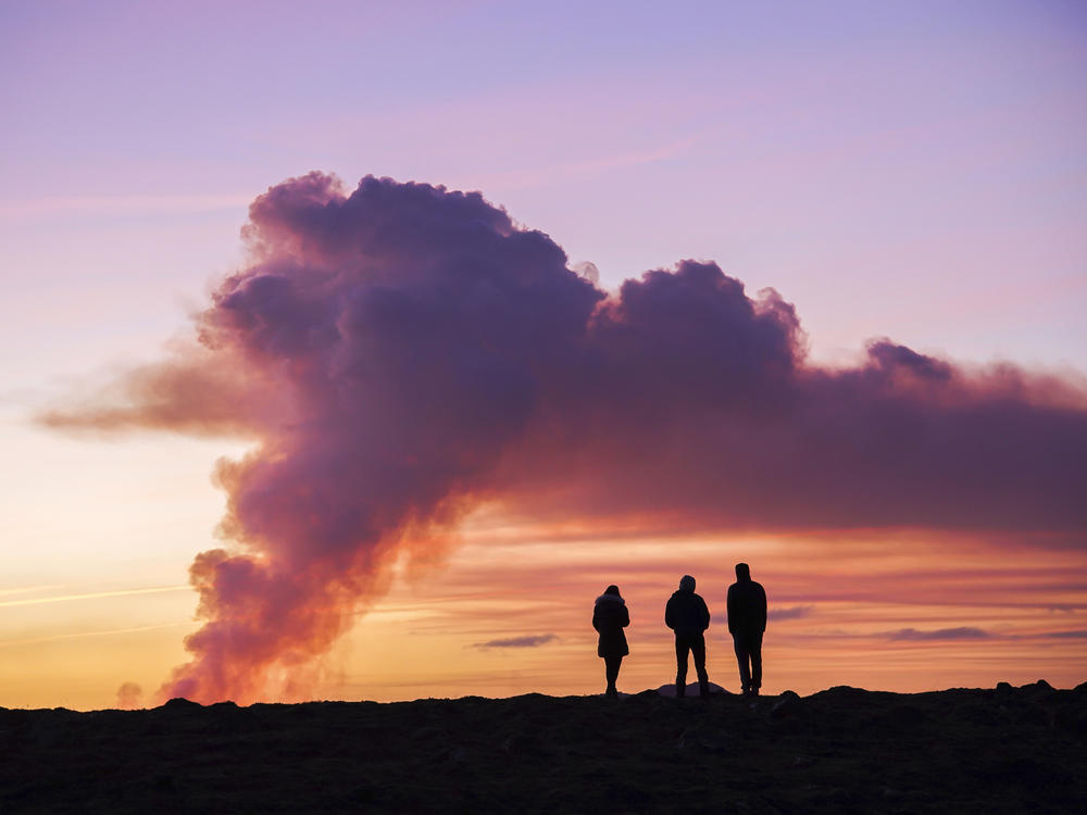People watch from the north as the volcano erupts near Grindavík, Iceland.