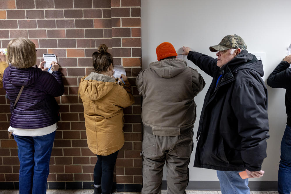 Iowans use the wall to fill out their registration paperwork on Caucuses night at Mitchell Elementary school on January 15, 2024 in Ames, Iowa.