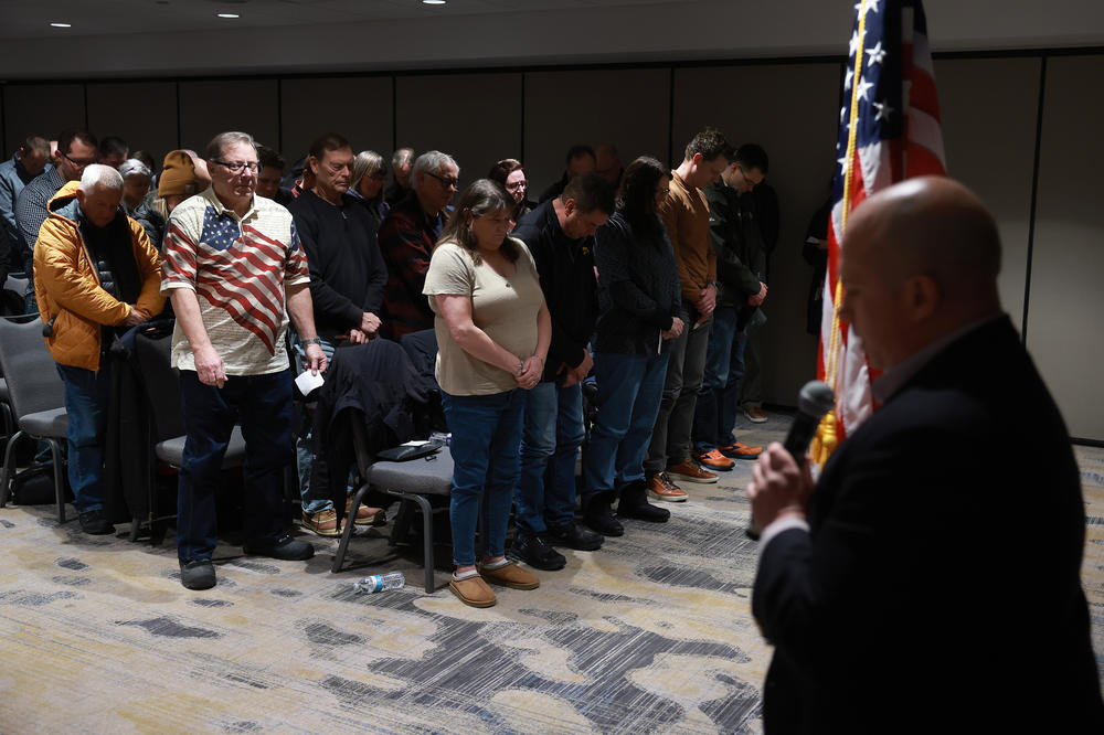 People pray as Andy Swanson (R), Caucus Site Leader, leads them at the start of the caucus on January 15, 2024, in West Des Moines, Iowa.