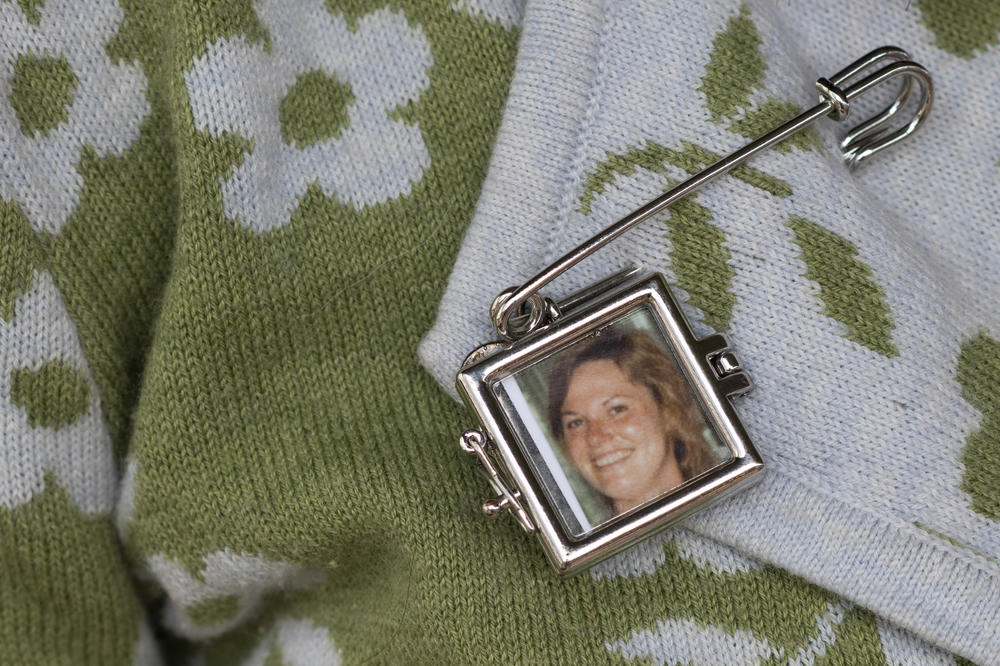 Lauren SinClair wears a pin with a photo of her mother, Susan SinClair, who died by suicide when Lauren was growing up.