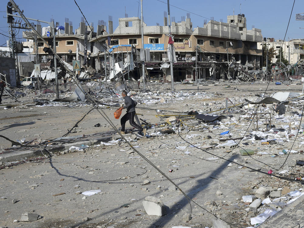 Palestinians walk through destruction by an Israeli bombardment in the Nusseirat refugee camp in Gaza on Tuesday, Jan. 16, 2024.