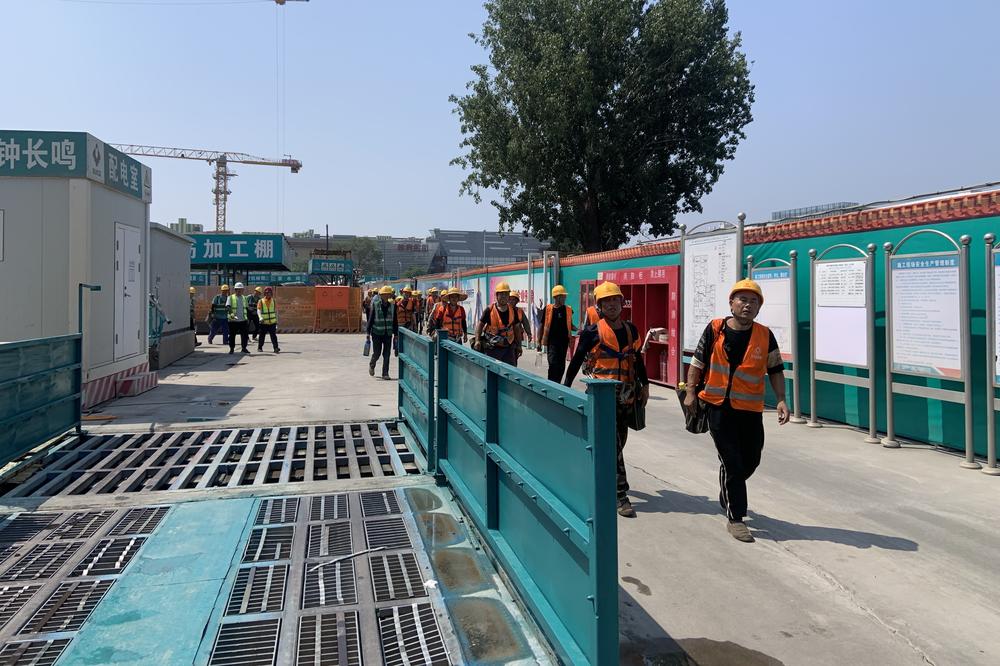 Construction workers in Beijing walk out of a site during their noon break.
