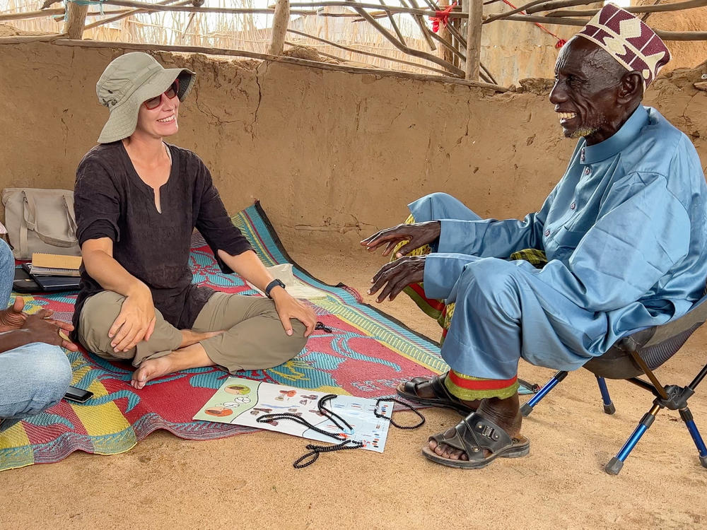 Anthropologist Carla Handley, center, meets with Wario Bala, right, to present the results of a DNA study she conducted seven years ago in his community in northern Kenya.
