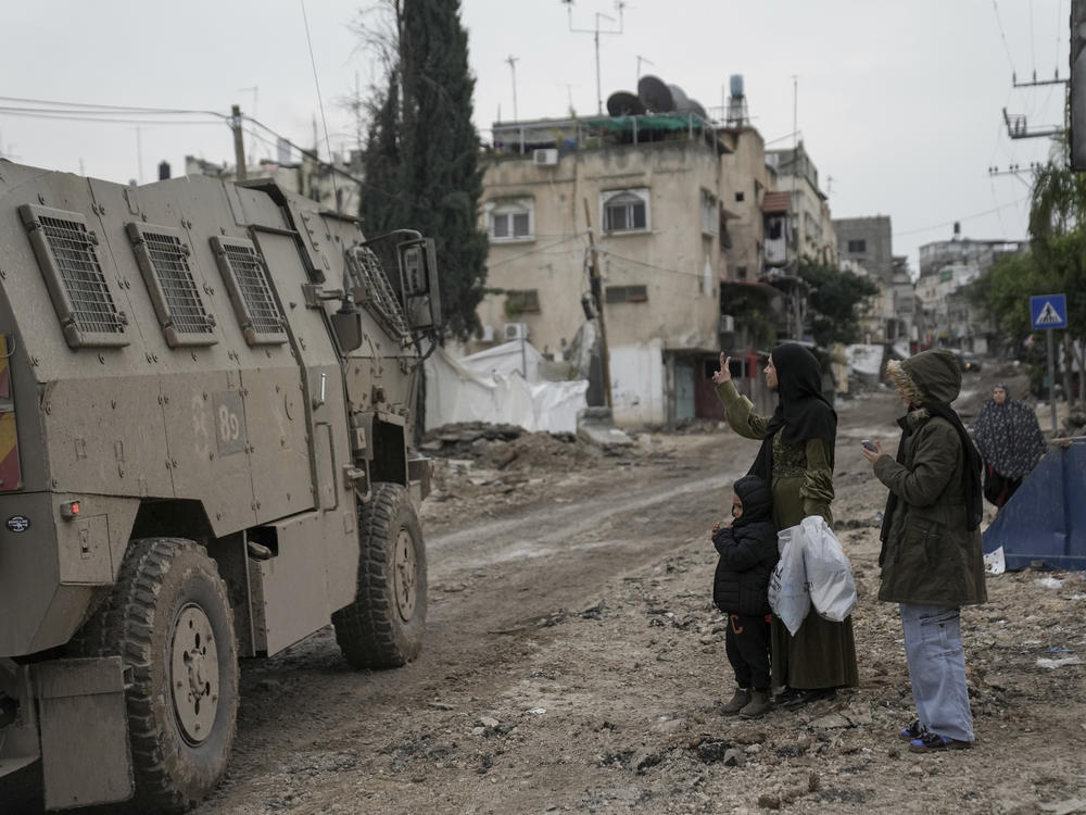 A Palestinian woman flashes a V-sign toward Israeli troops during an army raid in the Tulkarem refugee camp, West Bank, Wednesday, Jan.17, 2024.