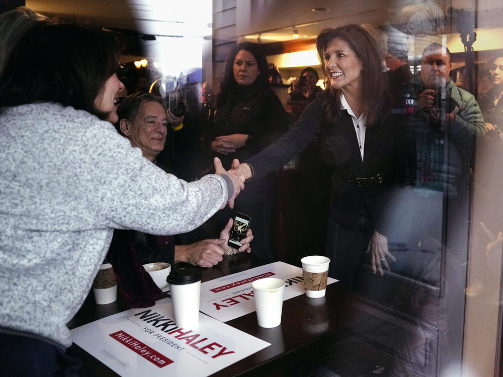 Republican presidential candidate former UN Ambassador Nikki Haley, seen through a storefront window, shakes hands with guests while visiting Kay's Bakery and Cafe, during a campaign stop on Friday in Hampton, N.H.