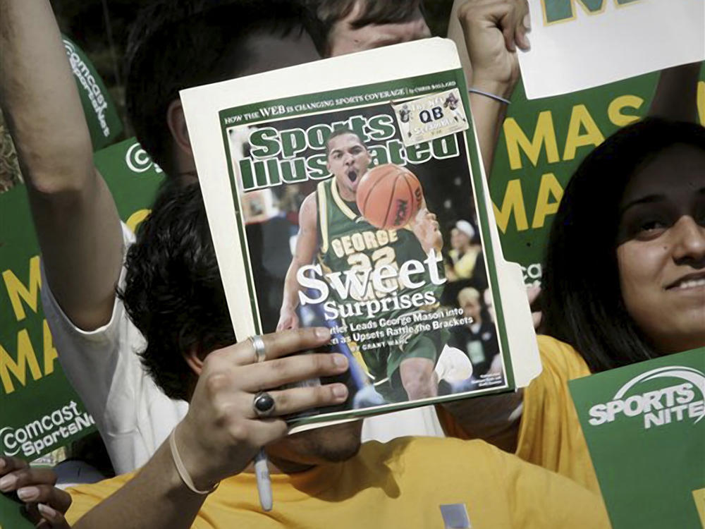 A George Mason University fan holds up the cover of a <em>Sports Illustrated</em> magazine at a send-off for the university's team on March 29, 2006, in Fairfax, Virginia. The union representing the magazine's staff said that SI's publisher plans to cut 