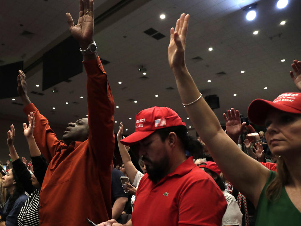 People raise their arms in prayer during a rally for evangelical supporters of President Donald Trump at the King Jesus International Ministry church on Jan. 3, 2020, in Miami.