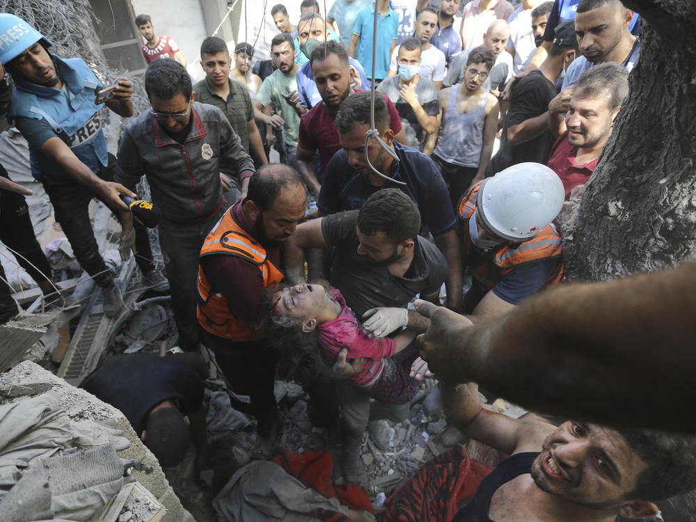 Palestinians rescue a child from under the rubble after Israeli airstrikes in Gaza City, Gaza Strip, on Oct. 18, 2023.