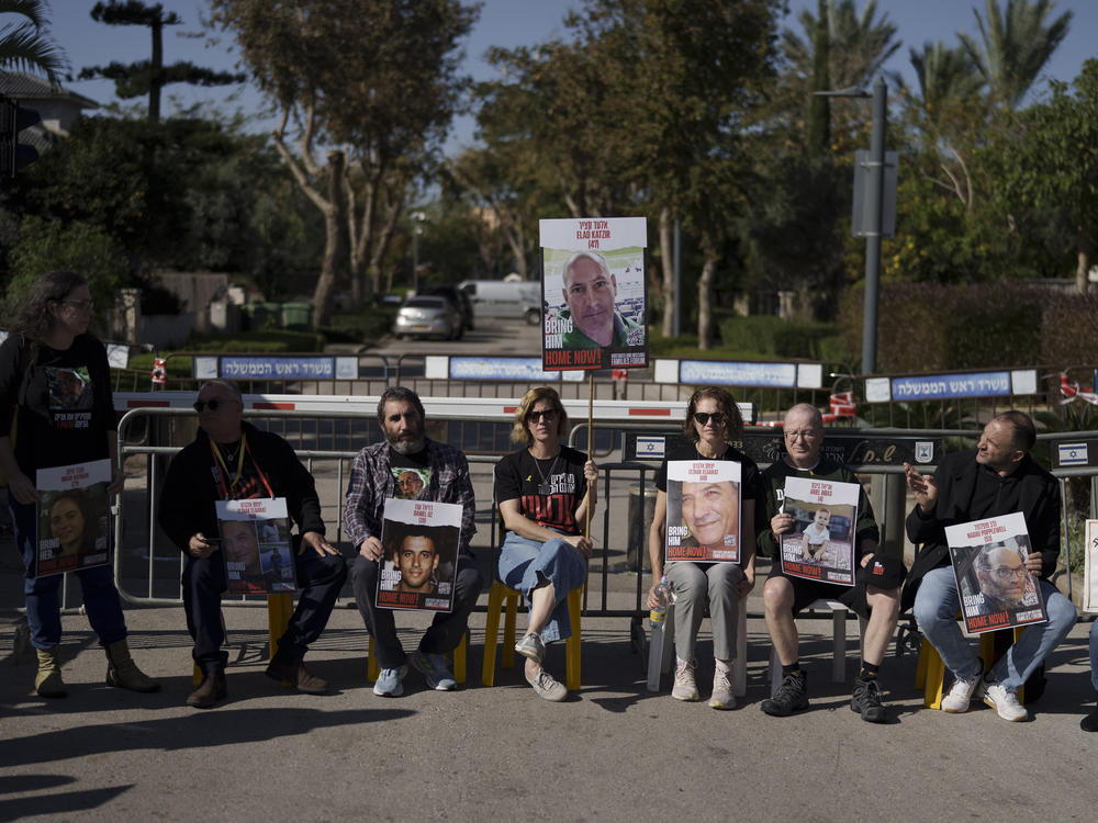 Relatives and friends of hostages sit on a street outside the private residence of the Israeli Prime Minister Benjamin Netanyahu, in Caesarea, Israel, Saturday, Jan. 20, 2024, in support of a father of an Israel hostage held in Gaza who has begun a hunger strike to protest the government's lack of visible progress on a new hostage deal.