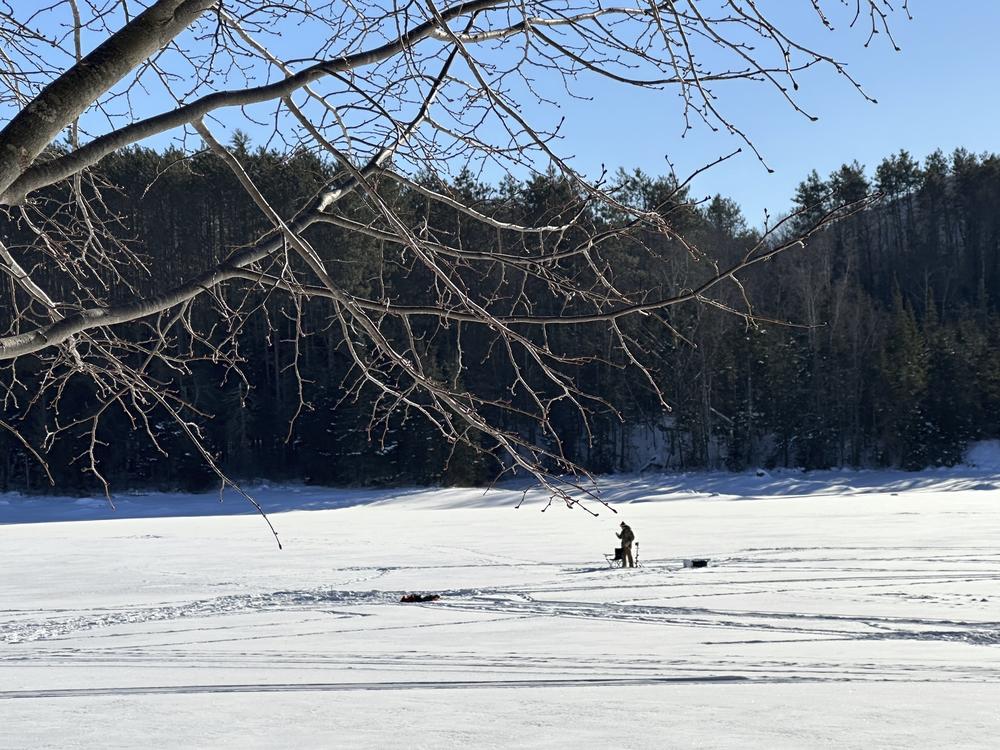An ice fisherman stands on the frozen Molly's Falls Pond in Marshfield, Vt., on Sunday.