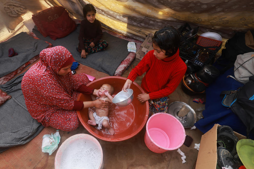 A woman gives a baby a bath inside a tent at a camp for displaced Palestinians in Rafah on Jan. 18.