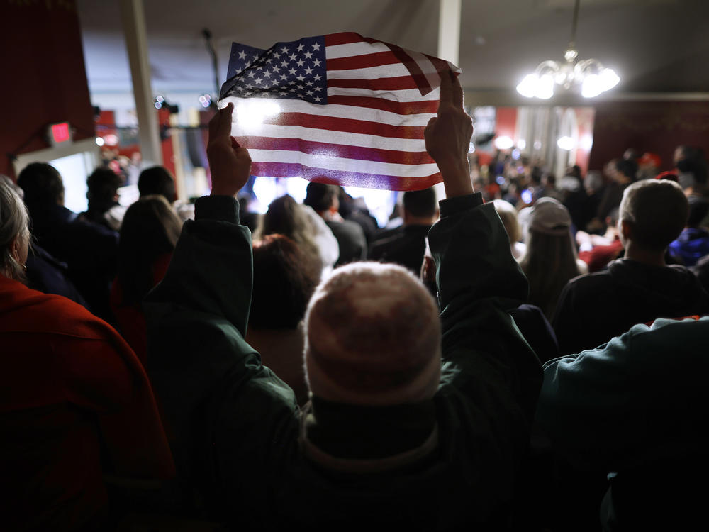 A woman holds up a small U.S. flag during a campaign rally by GOP presidential candidate and former President Donald Trump at the Rochester Opera House on Jan. 21 in Rochester, N.H.