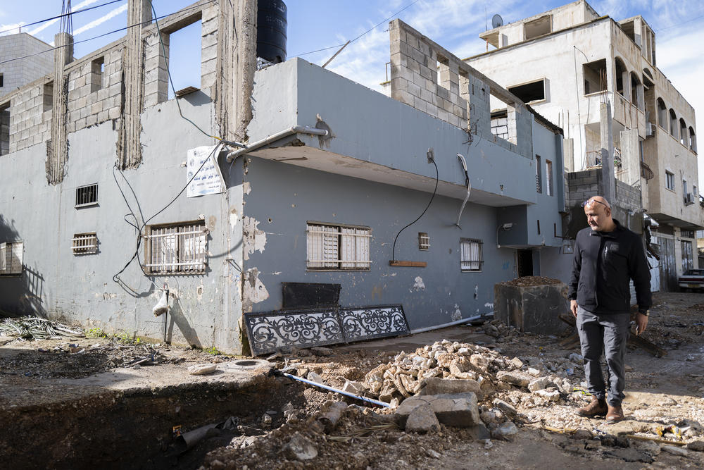 A block from the theater, Ashraf Jaradat stands outside his home, which he says was damaged in an Israeli military raid. He says he's left without an income since his shop was destroyed. 